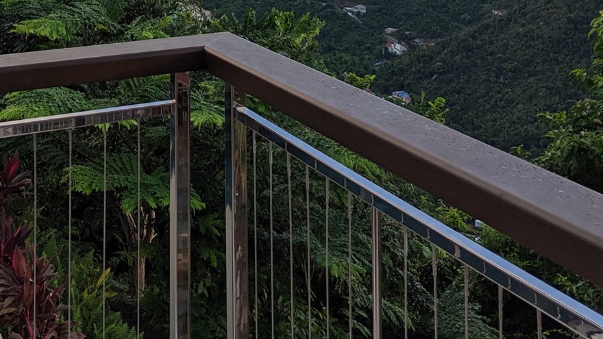 Mirror finish stainless steel railing posts with cable vertical infill.